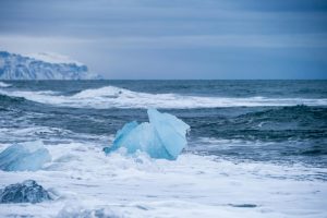 Icebergs on the scenic Diamond Beach in Iceland with rugged coastline and ocean waves.